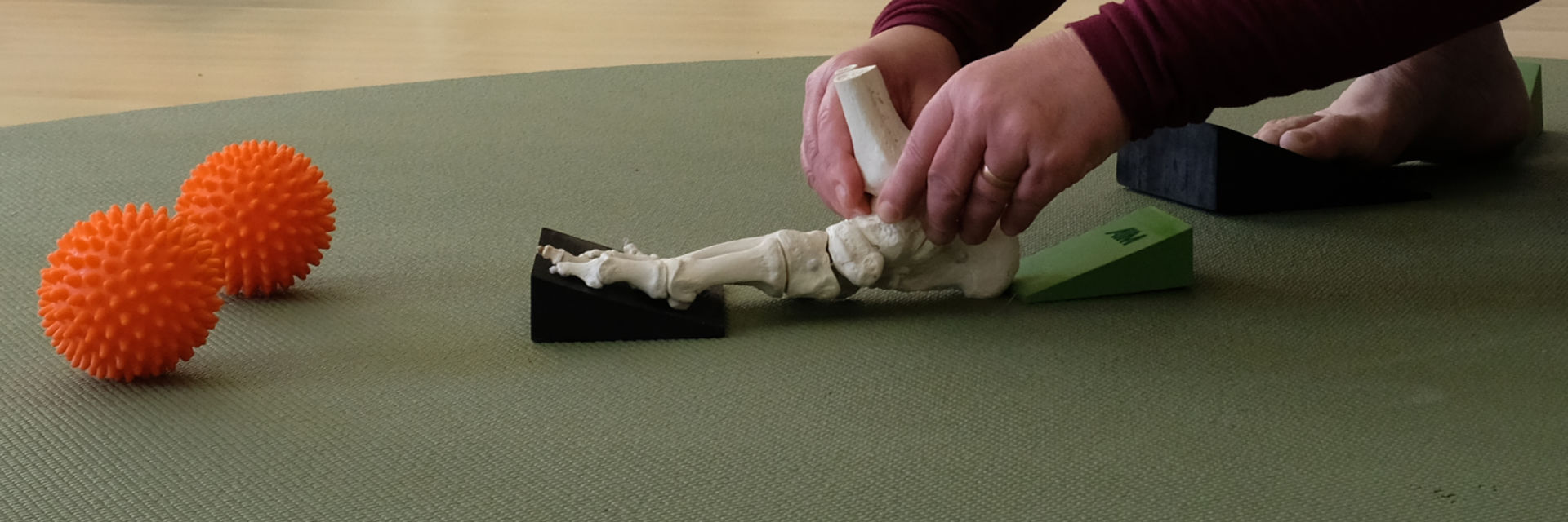 A foot skeleton on a wedge, beside two massage balls